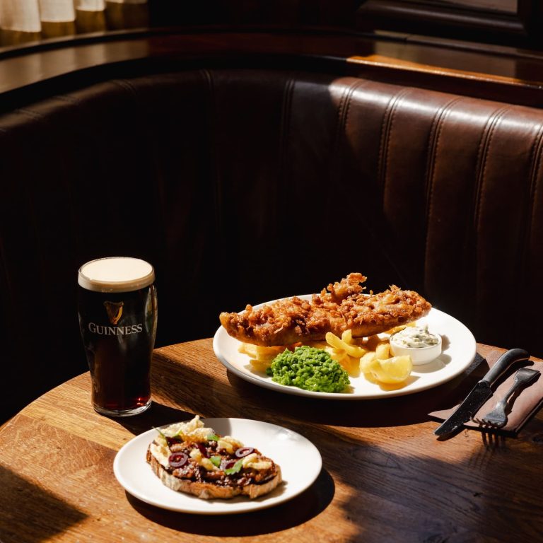 A pint of Guinness on a table in The Audley, alongside fish and chips